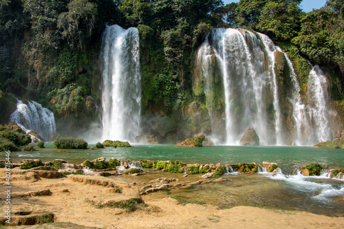 Ban Gioc-Detian Waterfalls on the border between the Vietnamese Province of Cao Bang and the Chinese Province of Guangxi on a beautiful day  framed by lush forest and clear water