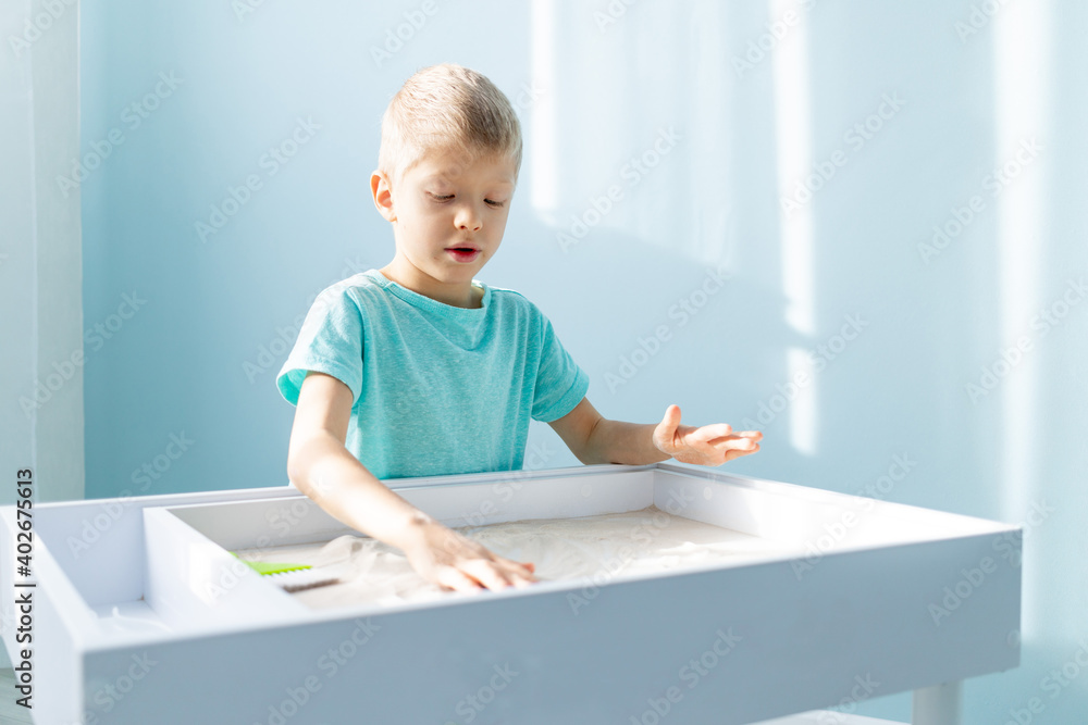 child plays with sand at home on the table, drawing on the sand child plays with sand at home on the table, drawing on the sand