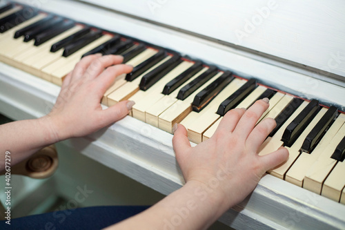 The woman plays the white piano. Female hands on the keys