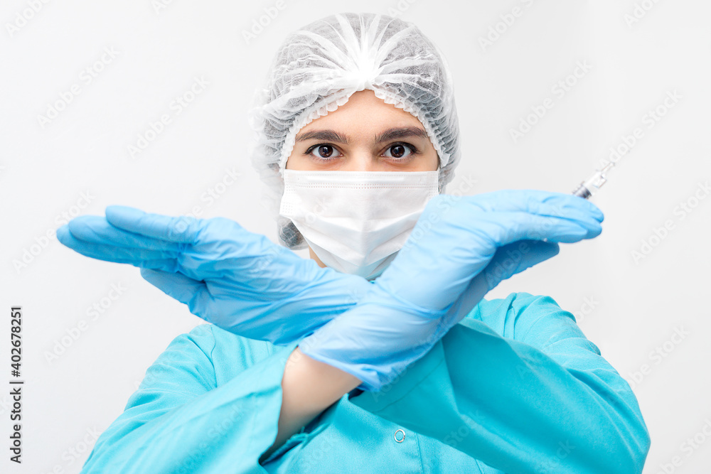 Portrait of female doctor in protective clothing,gloves and mask holding a syringe and showing forbidding gesture with her hands.Medicine and healthcare concept.Coronavirus vaccination concept Portrait of female doctor in protective clothing,gloves and mask holding a syringe and showing forbidding gesture with her hands.Medicine and healthcare concept.Coronavirus vaccination concept