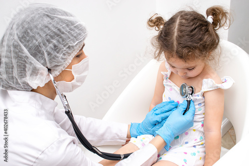 Pediatrician woman examining little girl by stethoscope in the medical office.Medicine and healthcare concept.