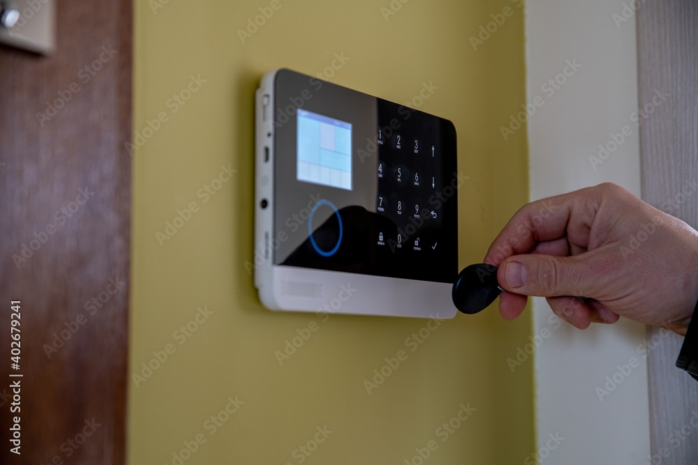 Man unlocking and disarming home security alarm with access pin card
