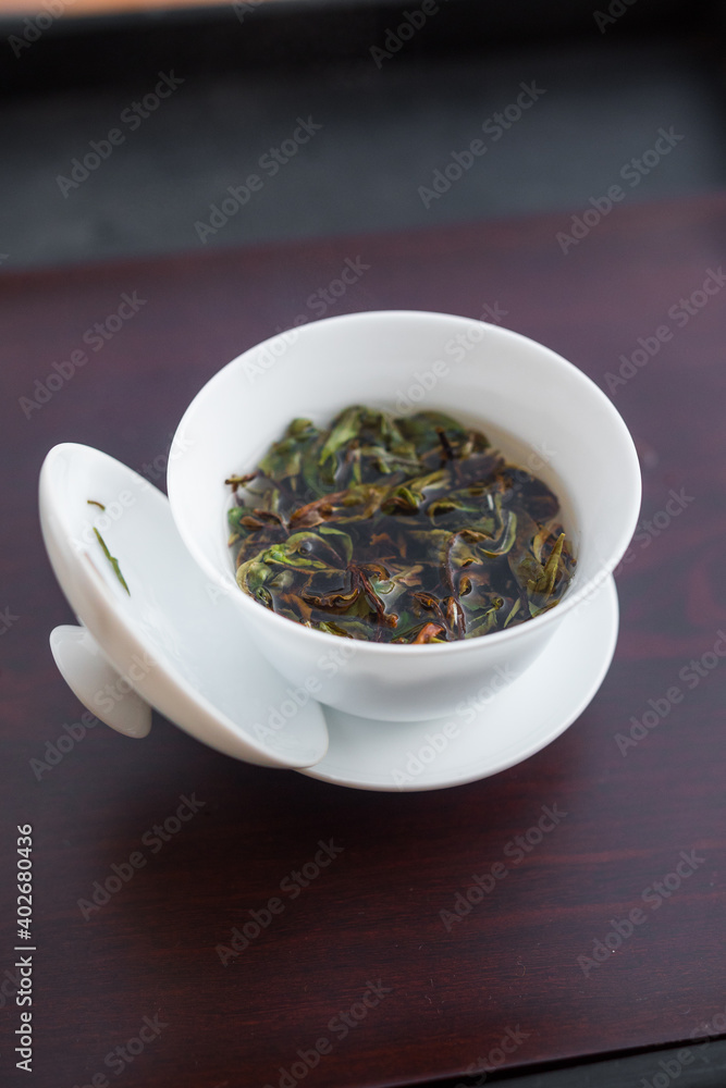 Rare high grade aged white tea steeping in a gaiwan with hot water. Beautiful full leaves processed by one of the best tea master in the world. Gong Fu Cha brewing, eastern style. Vertical shot. Rare high grade aged white tea steeping in a gaiwan with hot water. Beautiful full leaves processed by one of the best tea master in the world. Gong Fu Cha brewing, eastern style. Vertical shot.
