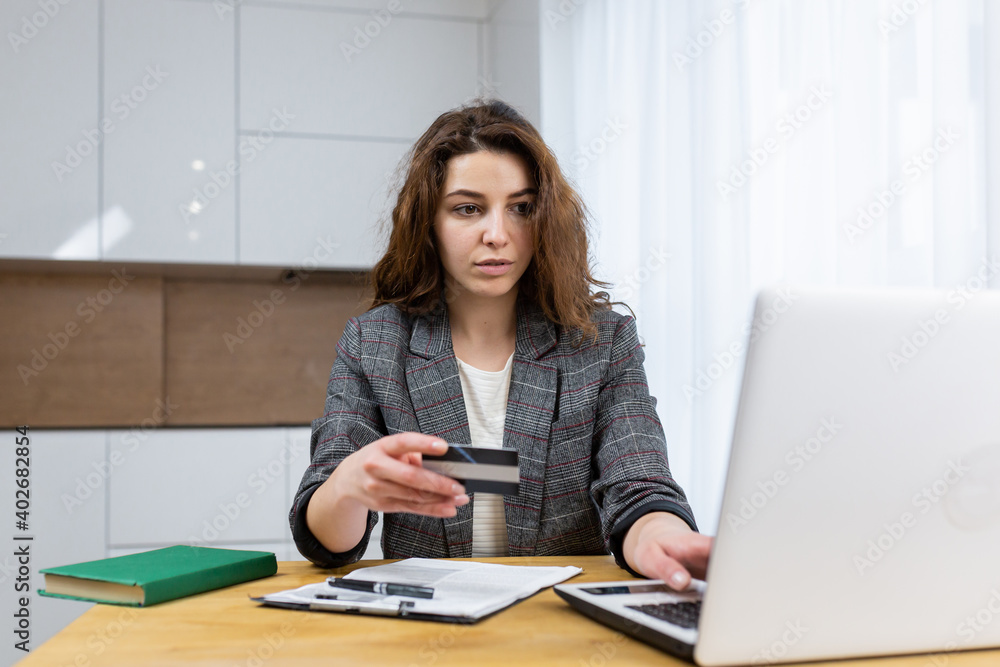 The woman is relaxing at home, shopping online, using a laptop and a credit card The woman is relaxing at home, shopping online, using a laptop and a credit card
