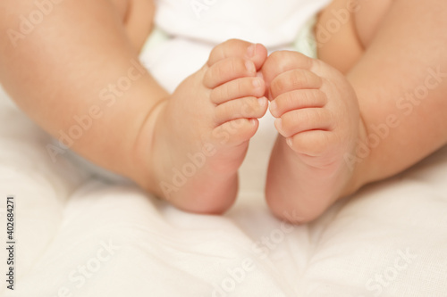 Legs of infant on the white blanket, bedroom, blurred background