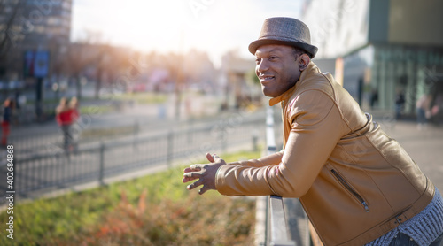 Stylish happy young african american man in hat and yellow jacket on city streets