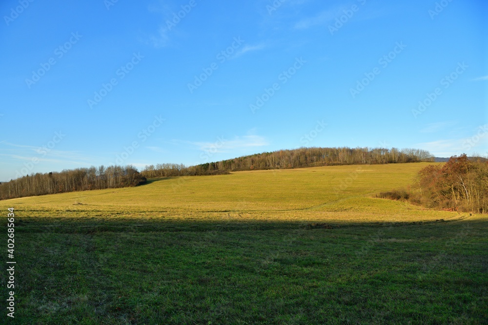View of the landscape with a large meadow and blue sky during a sunny autumn