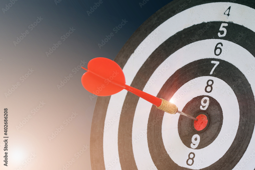 Close up Red Dart arrow hitting in the target center of dartboard for background Target, business, achieve and success concept, on the game focuses on success.. Close up Red Dart arrow hitting in the target center of dartboard for background Target, business, achieve and success concept, on the game focuses on success..