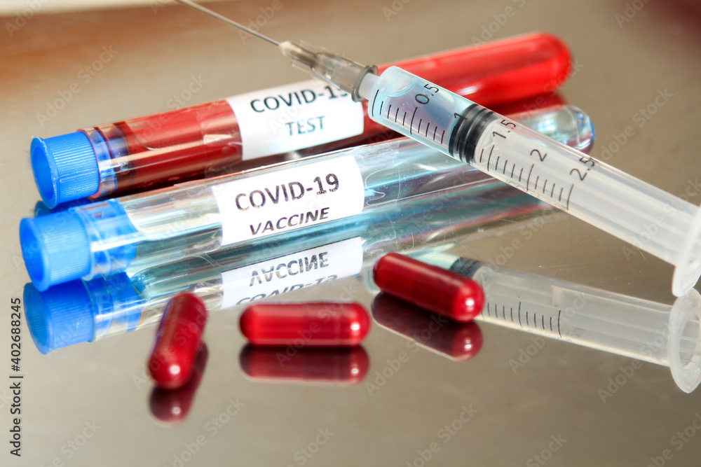 Syringe next to test tube with Covid-19 vaccine Syringe next to test tube with Covid-19 vaccine