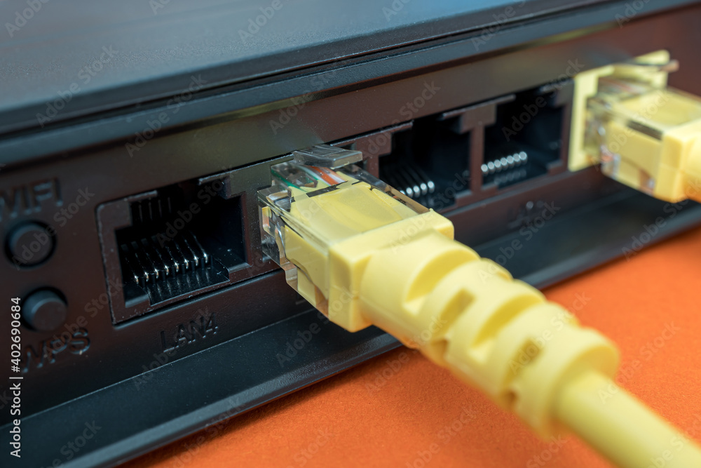 patch cords are yellow inserted into the ports of the router to access the Internet. router on a blue background patch cords are yellow inserted into the ports of the router to access the Internet. router on a blue background