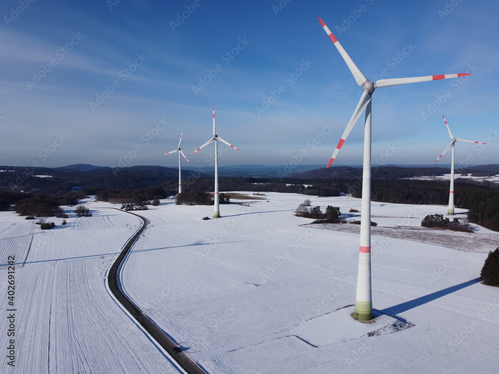 Aerial view of a wind farm in a winter landscape during sunset. Aerial view of wind turbines during sunset.