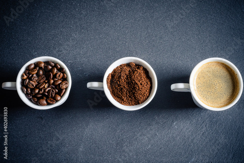 3 Tassen mit Kaffeebohnen, Kaffeepulver, Kaffee auf einer Schiefertafel