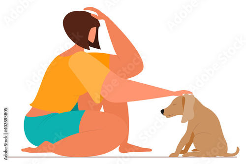The girl sits and caresses a small dog on the head. Friendship with a pet. Human-animal communication.