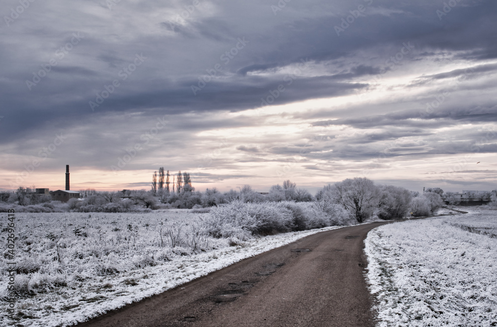 Einsamer Weg in einer Winterlandschaft mit vielen Wolken