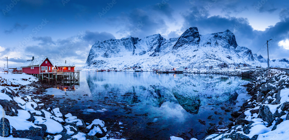 Scenic Lofoten Islands winter scenery with traditional Rorbuer fisherman cabins during blue hour at dusk, Reine, Norway