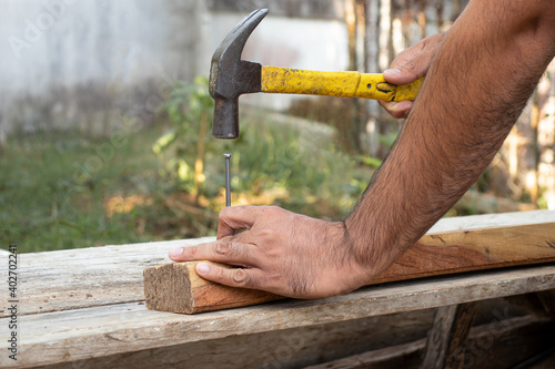 The carpenter was hammering nails into the wood with a hammer.