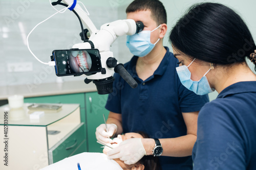Modern dental clinic with microscope tool for treatment patients. Doctor hand in protective glove putting medical microscope. Man dentist uses microscope. Medical equipment, dental clinic