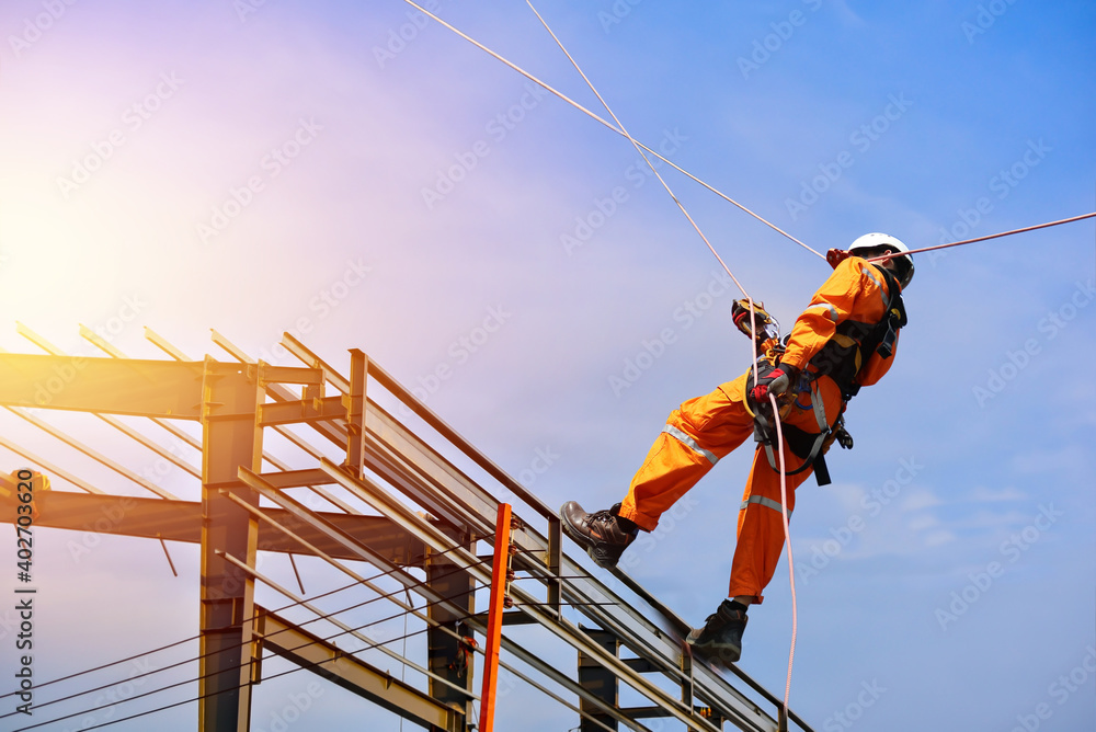 Safety man worker sprinkle with equipment safety harness on steel construction site and building structure frame with blue sky background Safety man worker sprinkle with equipment safety harness on steel construction site and building structure frame with blue sky background