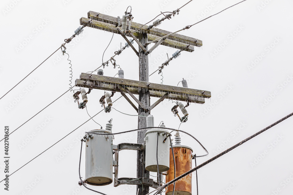 Ice on electrical utility pole and power line from freezing rain. Concept of winter storm and power outage. Ice on electrical utility pole and power line from freezing rain. Concept of winter storm and power outage.