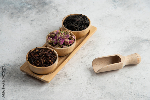 Wooden bowls with dried roses and infusion on a wooden board