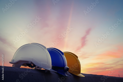 white, Blue and Yellow Safety hard helmet sunset background, fore safety concept.