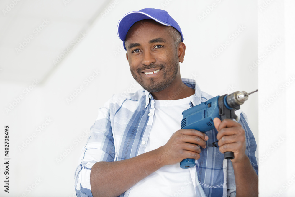construction worker drilling hole in wall in a new house construction worker drilling hole in wall in a new house