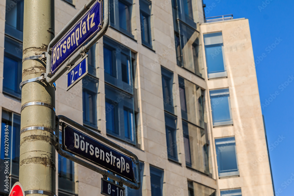 Two blue street signs stock exchange place and stock exchange street on a gray lamppost with fixings. House with window facade in the background Two blue street signs stock exchange place and stock exchange street on a gray lamppost with fixings. House with window facade in the background