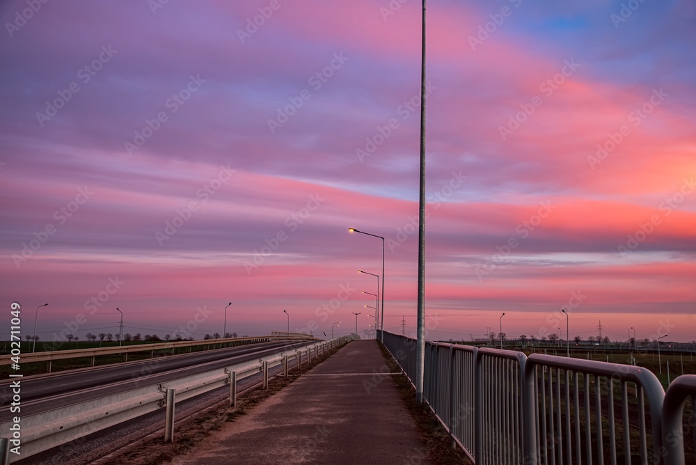 sunset over the bridge. street lights against the pink sky