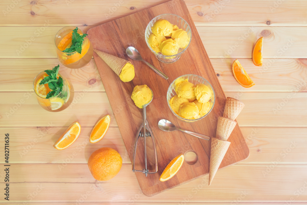 Orange ice cream, orange lemonade, ice cream cones and fresh oranges on