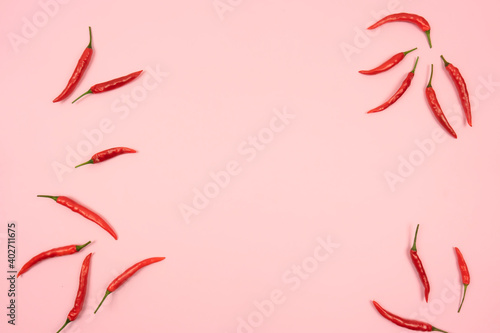 Red hot chilli peppers lie on a pink background table. Copy space. Frame for text