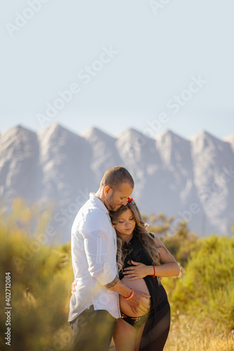 Pregnant woman hugged and kissed by her partner in a romantic way outdoors. valentine concept