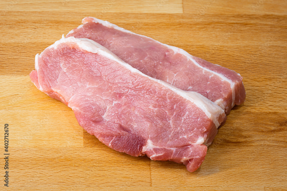 Sliced pieces of raw red pork meat on the wooden cutting board. Food close-up object photo. Studio shot. Sliced pieces of raw red pork meat on the wooden cutting board. Food close-up object photo. Studio shot.