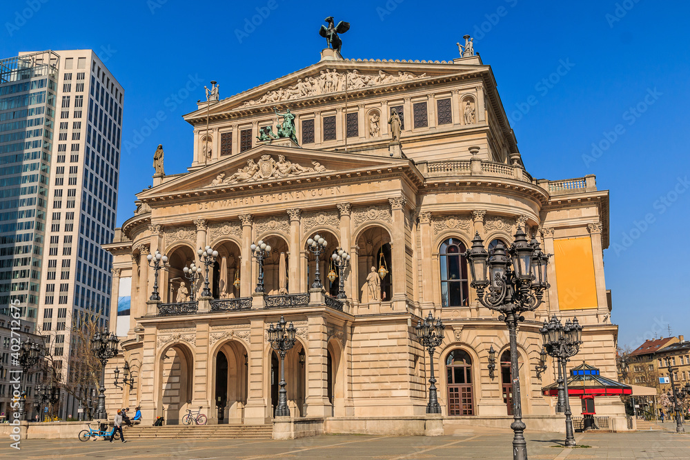 Old Frankfurt Opera in the city center. Historic building in springtime in sunshine. Street lights with space in front of the building. Business buildings in the background