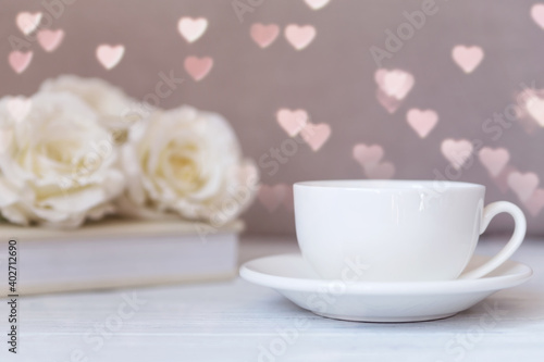 Valentines day coffee mug, cup on the wooden table and heart bokeh background with roses