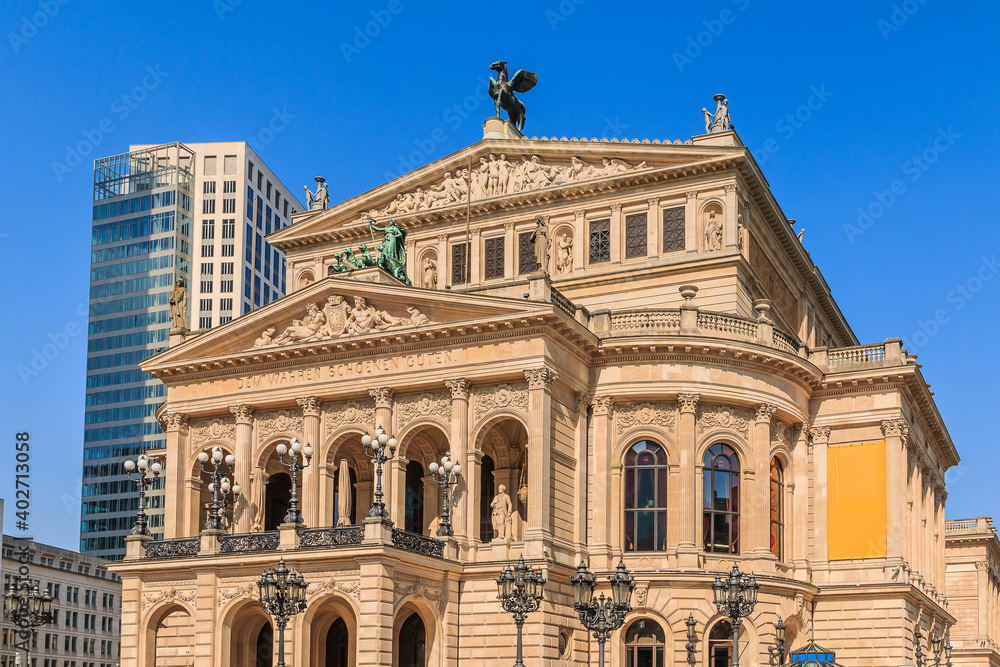 Obraz premium Historic building of the old opera house in Frankfurt in springtime with sunshine. Public square in the center of the city with street lamps in front of the building.