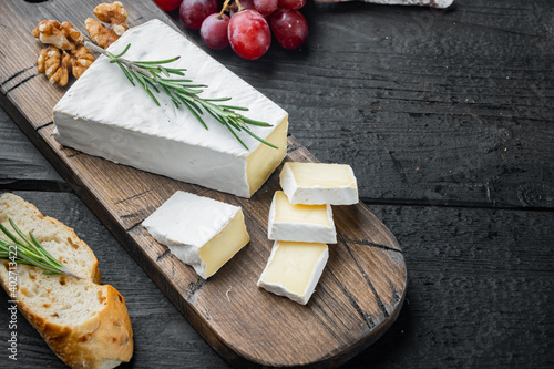 Delicious brie cheese, on black wooden table  with copy space for text photo