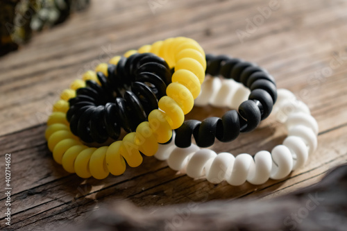 Fashionable and modern elastic hair springs. Different colors of stretching hand bracelets on wooden background, stand
