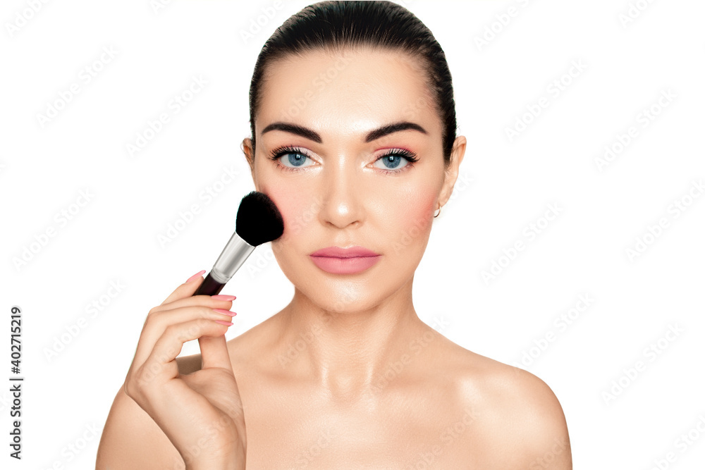 Portrait of a girl on a white background. Blush brush in hand near face..