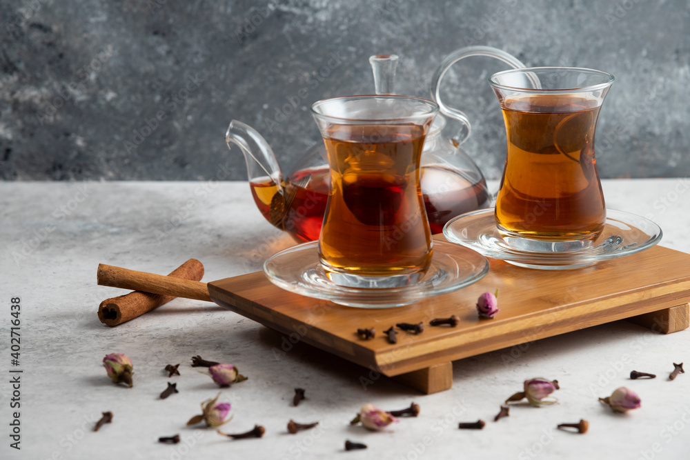 Two glass cups of tea with cinnamon sticks and dried roses Two glass cups of tea with cinnamon sticks and dried roses