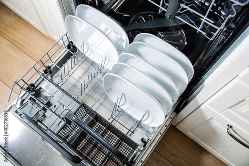 An open dishwasher with clean plates, top view. Modern kitchen appliance.