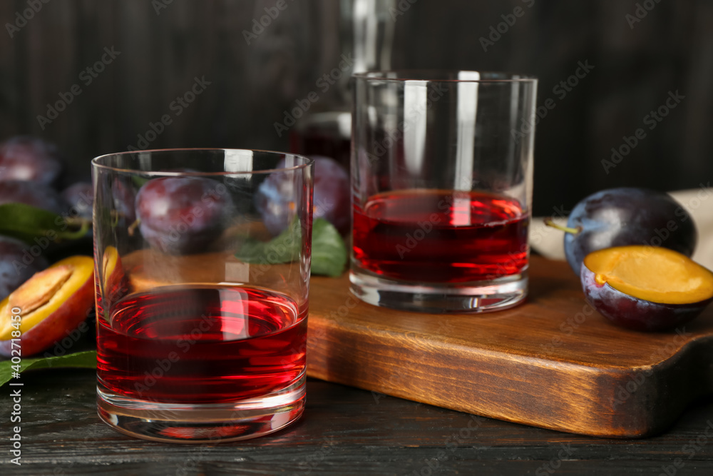 Delicious plum liquor and ripe fruits on black wooden table. Homemade strong alcoholic beverage Delicious plum liquor and ripe fruits on black wooden table. Homemade strong alcoholic beverage