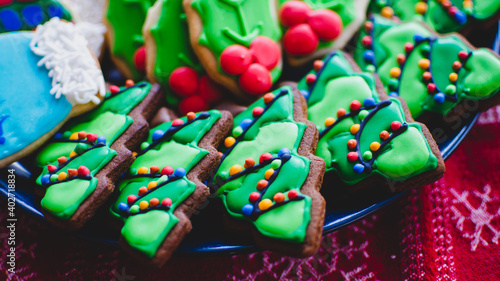 Close-up of beautifully decorated gingerbread Christmas cookies made to look like lit-up Christmas trees on a platter