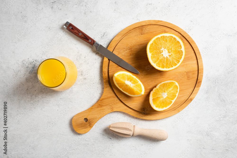 Sliced fresh oranges with wooden reamer on a marble background Sliced fresh oranges with wooden reamer on a marble background