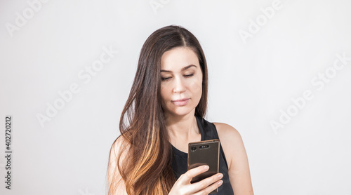 Young Brunnete looks in the phone. White background