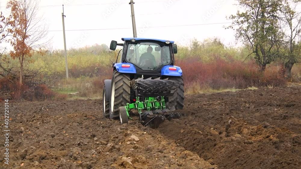 plowing in the field by a tractor with a trailed unit plowing in the field by a tractor with a trailed unit