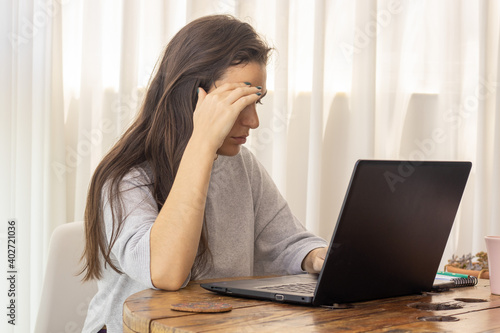 worried young woman at home using laptop