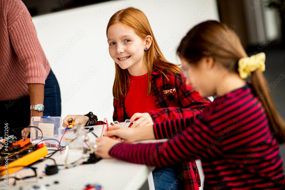 Cute little girls programming electric toys and robots at robotics classroom Cute little girls programming electric toys and robots at robotics classroom