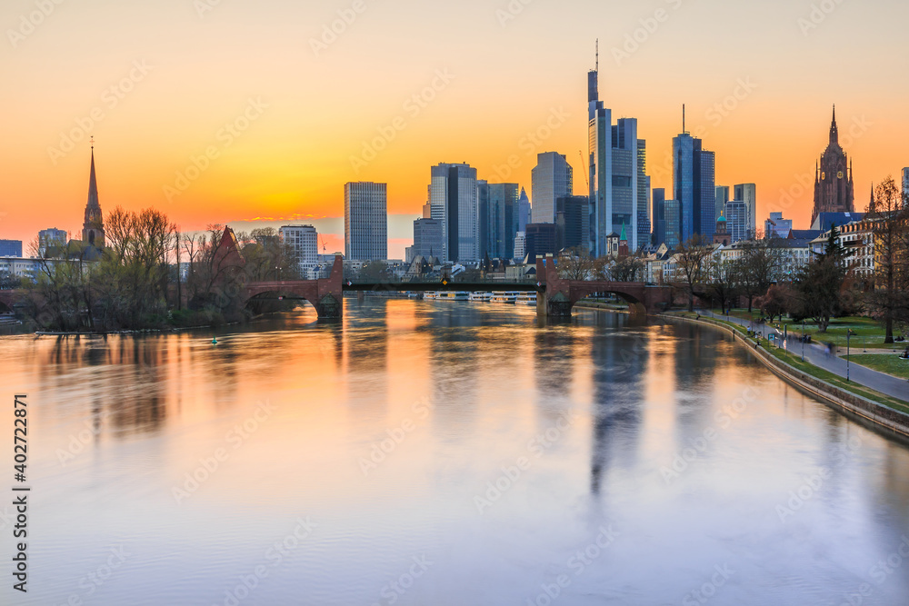 Sunset over the Frankfurt skyline in spring. Skyscrapers and skyscrapers from the financial and business hub of the city. River Main with reflections and bridge with park
