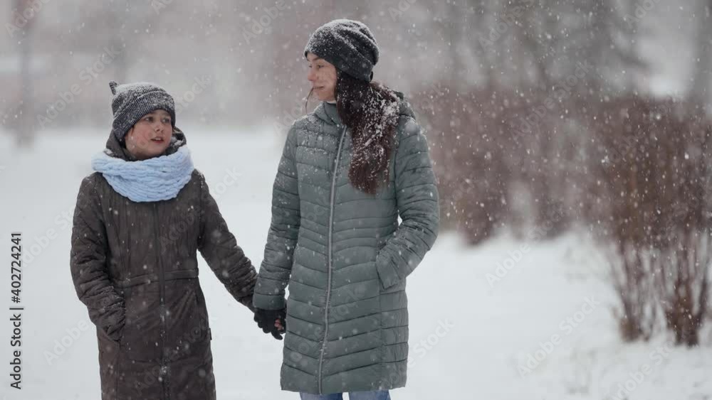 family of mother and daughter is walking in winter park, holding hands and chatting, weekend family of mother and daughter is walking in winter park, holding hands and chatting, weekend