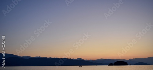 Silhouette of a fishing boat and the dark blue mountains in the background